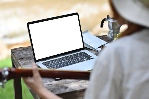 istock Rear view with Young Millennials traveller playing guitar while opening lyrics on the laptop, Empty screen of Laptop, Park and Outdoor concept. 2163255231