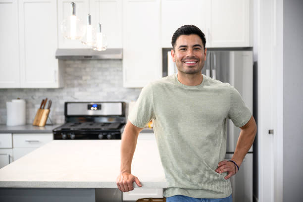 istock Smiling Latin American man leaning with one hand on kitchen island 2163257936