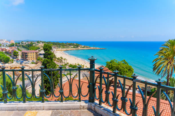 Elegant iron railings framing a beautiful beach and the Mediterranean Sea in Tarragona, Spain.