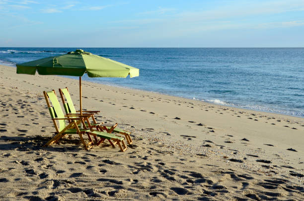 Rows of straw parasols and sunloungers on the beach at Manta Rota, Algarve, Portugal.