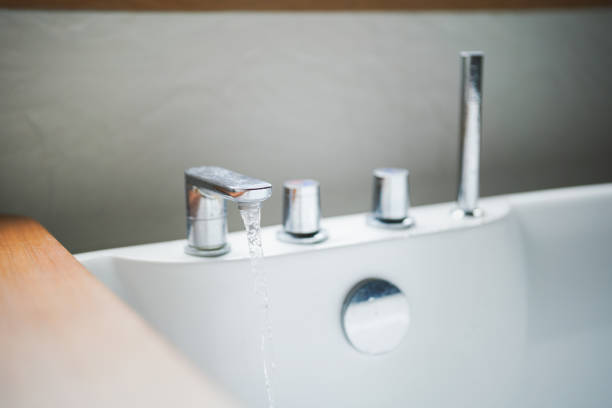 Water flowing from the faucet into luxury bathtub, preparing for spa recreation. Home interior decoration with lifestyle. Close-up and selective focus.