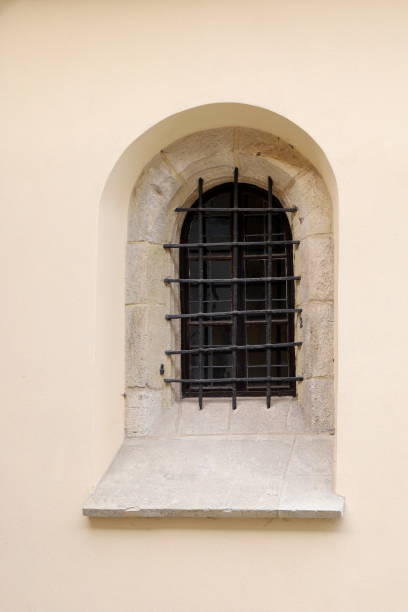 istock A barred window with an arch in a medieval building. 2163267441