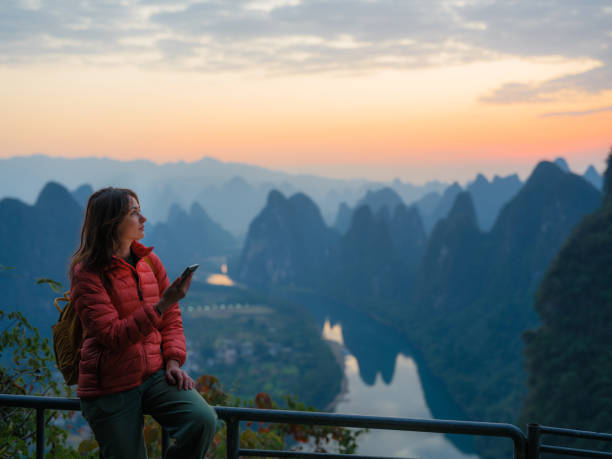 istock Woman using smartphone on viewpoint overlooking Li river in Guilin, China 2163267669