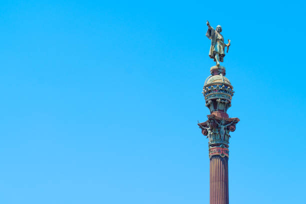Barcelona, Spain - July 16, 2024: Columbus monument featuring a statue pointing towards the sea isolated on a clean blue background with copy space.