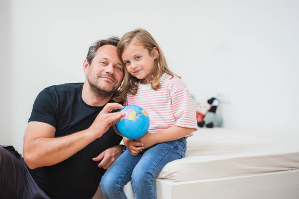 istock Father and daughter hugging and holding a globe 2163276908