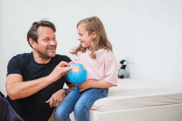 istock Father and daughter sharing a laugh and playing with a globe 2163276943