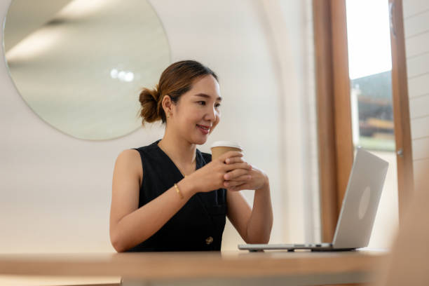 istock Smiling Woman Enjoying Coffee While Working on Laptop 2163277641