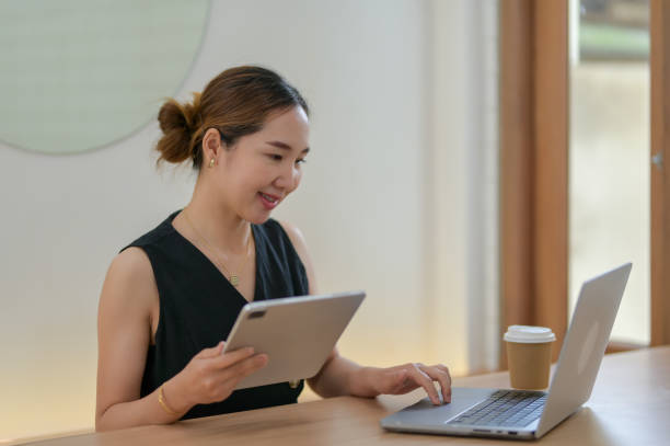 istock Businesswoman Multitasking with Tablet and Laptop 2163281563