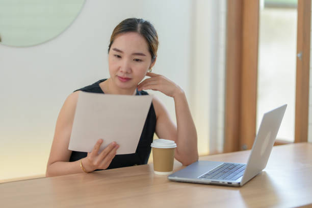 istock Smiling Woman Enjoying Coffee While Working on Laptop 2163282830