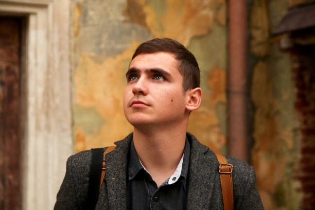 istock portrait young man classical background. Serious young man with blue eyes. 20s years. Handsome man outdoors portrait. Lifestyle. Student looks up. Closeup 2163285946