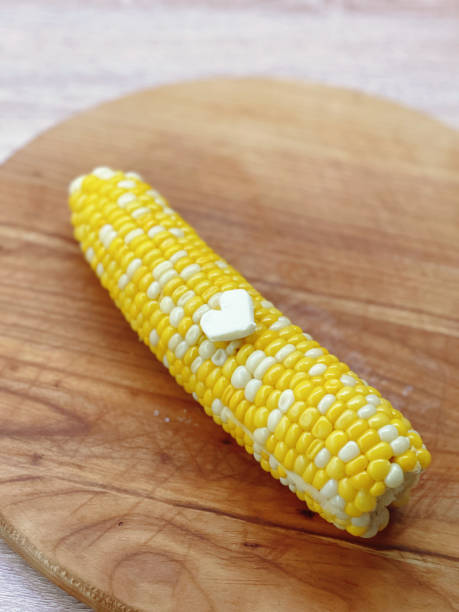 istock Corn on the cob with heart-shaped butter on a wooden board. 2163294629