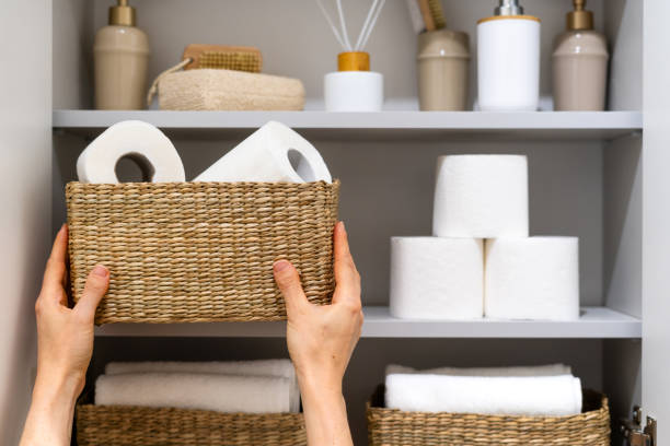 istock Hands placing toilet paper rolls in wicker basket on shelf 2163299899