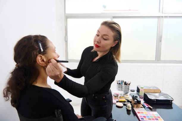 istock Makeup artist applying makeup to woman in professional studio setup 2163305358