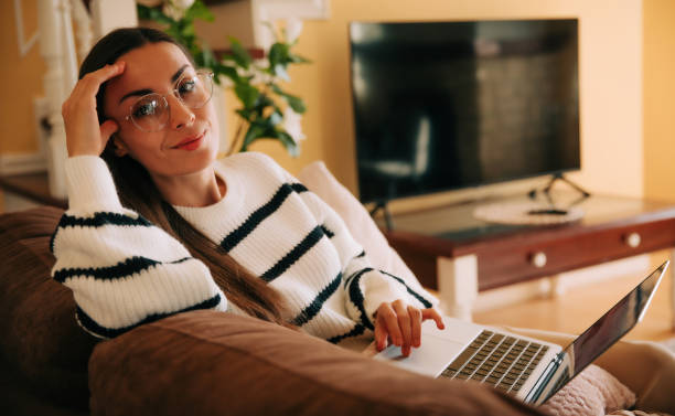 istock Beautiful happy confident woman in eyeglasses working on comfortable couch, using laptop at home, happy girl chatting with friends in social network, watching movie, shopping online, freelancer 2163306058