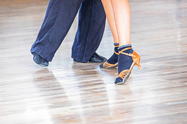 dancer practices in worn out leather shoes on the floor with a teacher