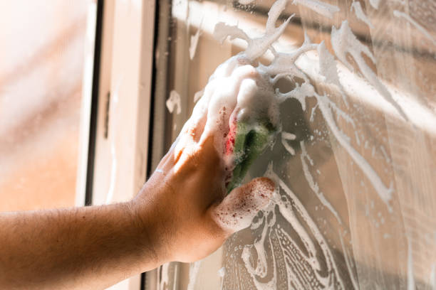 istock Man cleaning window using window cleaning squeegee and cleaning sprayer, cleaning services concept. Housework and housekeeping concept 2163311622