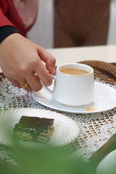 istock A woman holding a cup and saucer. 2163314885