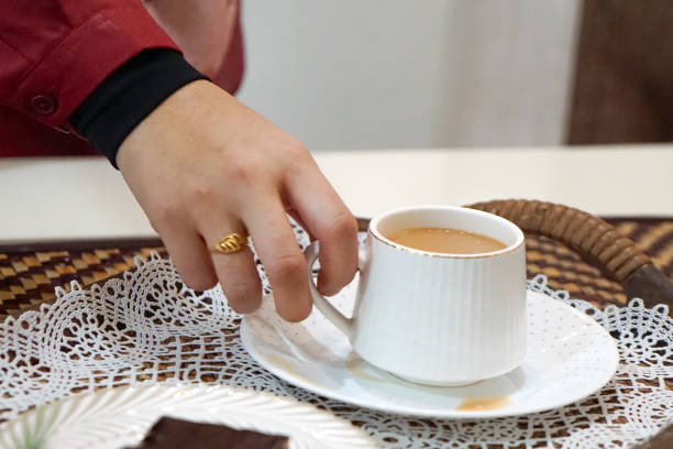 istock A woman holding a cup and saucer. 2163314941