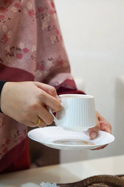 istock A woman holding a cup and saucer. 2163314988