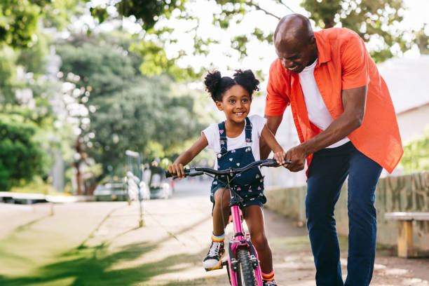 istock Happy father teaching daughter to ride bicycle in park 2163318500