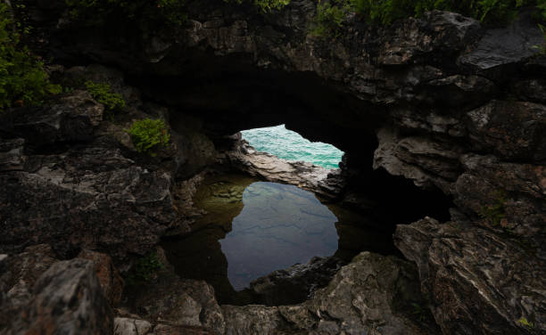 A serene landscape featuring rocky formations, the expansive lake, and trees, captured on a rainy day.