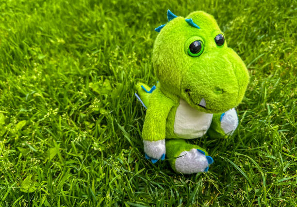 istock Light green stuffed dinosaur, green grass background 2163326975