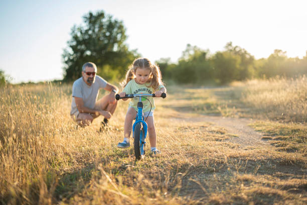 istock Fatherhood. Caring Dad Teaching Daughter to Ride Bicycle. 2163330093