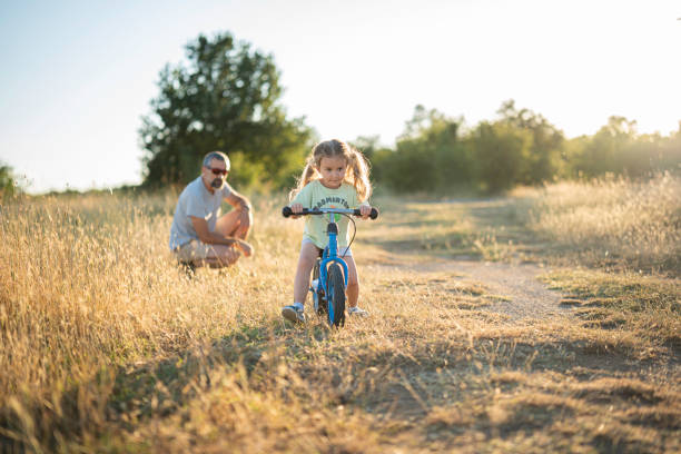 istock Fatherhood. Caring Dad Teaching Daughter to Ride Bicycle. 2163330096
