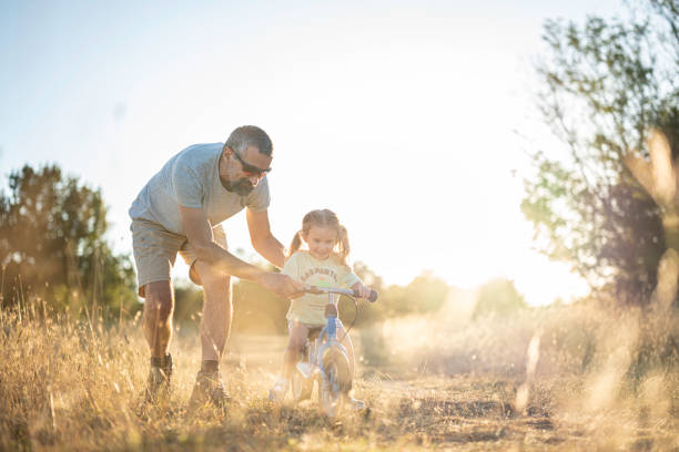 istock Fatherhood. Caring Dad Teaching Daughter to Ride Bicycle. 2163330105