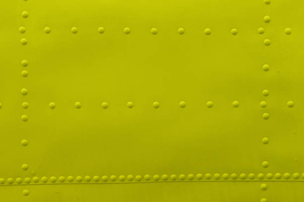 Abstract background made of sheet metal with rivets, yellow background.