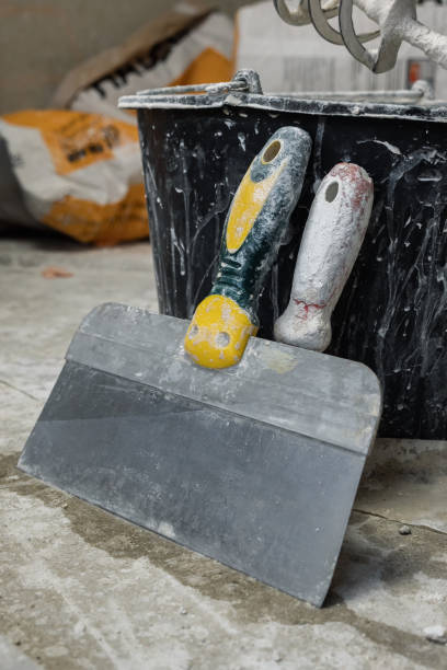 istock Two trowels standing on a concrete floor leaning on a black plastic bucket 2163331327