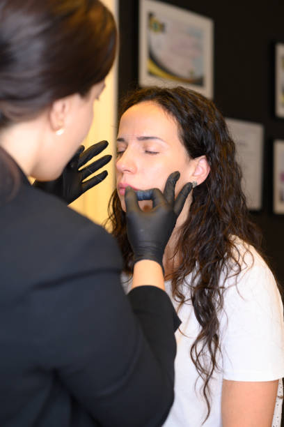 istock Beautician applying permanent eyebrow makeup on young hispanic 30s woman 2163331952