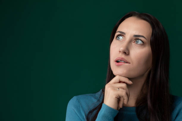 istock Woman Looking Up With Hand on Chin 2163332763