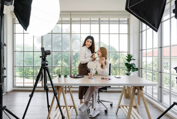 istock Two asian women creating content for social media. They are using a studio setup that include a camera mounted on a tripod, lighting equipment and various makeup product on the table. 2163352250