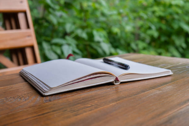 Empty white open paper notebook in wooden table outdoors in garden. Concept of self reflection discovery journal, writing gratitude