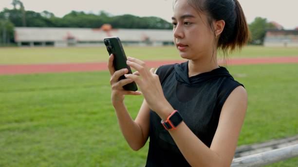 istock A woman is looking at her phone while standing on a grassy field 2163357109
