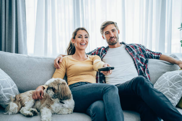 istock Cute young couple cuddling while watching tv. 2163365329
