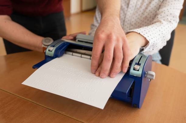 istock A man teaches a blind woman to type on braille machine. 2163367075