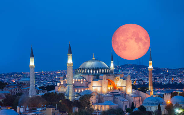 Full moon sets over the minarets of the Blue Mosque in IstanbulPicture taken from the Asian side of the Bosphrous on a 600mm lens to give this perspective