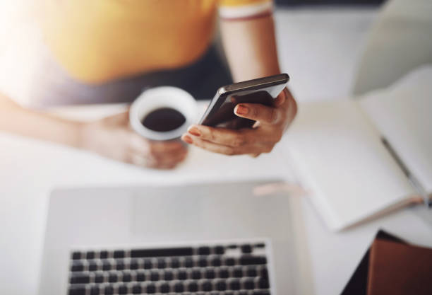 istock Hands, searching on smartphone with laptop, coffee and work in home office or shopping, browsing and mobile communication. Closeup, woman and social media, internet or online, work or ecommerce 2163367595