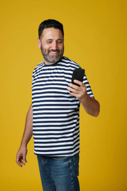 istock Dynamic Portrait handsome man.  Using Smart phone. Striped Blue White Navy T-Shirt, casual lifestyles.  Yellow background. 2163369026