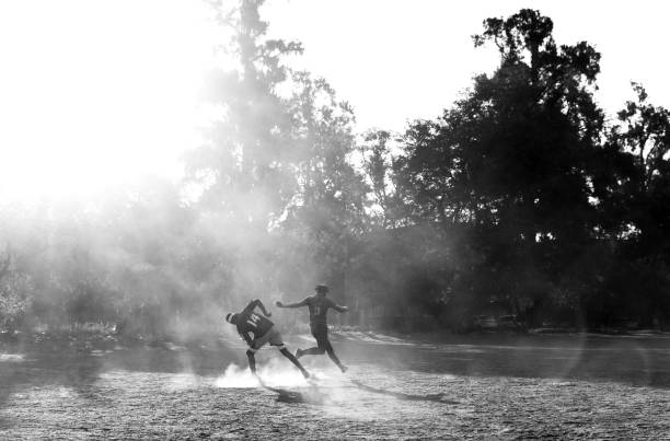 Young men play a game of late afternoon football on a dry dusty dirt field in Bulawayo, Zimbabwe on June 18th 2023