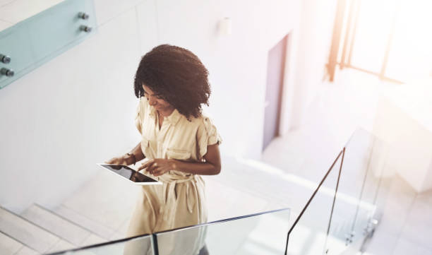 istock Business woman, tablet and walking on stairs for communication, networking and check schedule. African person, tech and steps with social media, conversation and online meeting calendar for work 2163372652