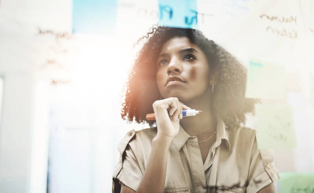 istock Writing, thinking and business woman at board with planning, creative solution and notes. African employee, research and problem solving idea with moodboard for project strategy and agenda in office 2163372661