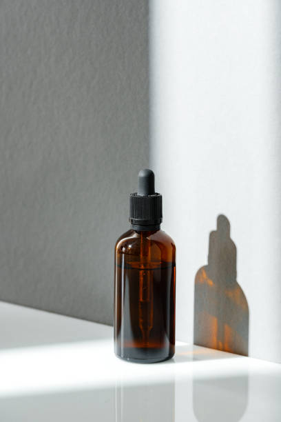 istock Amber Glass Dropper Bottle With Sunlight Shadow on White Surface 2163372923