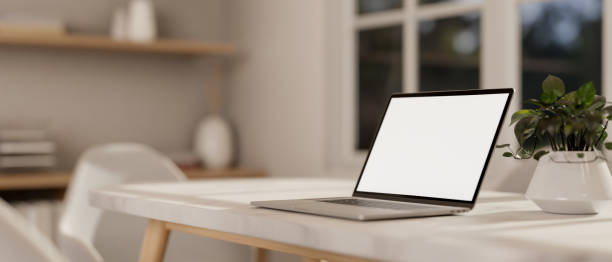 istock A laptop computer with a white-screen mockup on a white table in a minimalist white room. 2163373529