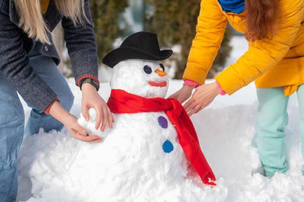 istock Two faceless Caucasian women are making a snowman. Winter fun. 2163373759