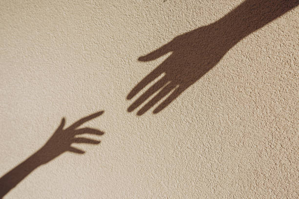 istock Shadows of hands reaching each other on the wall. 2163374907