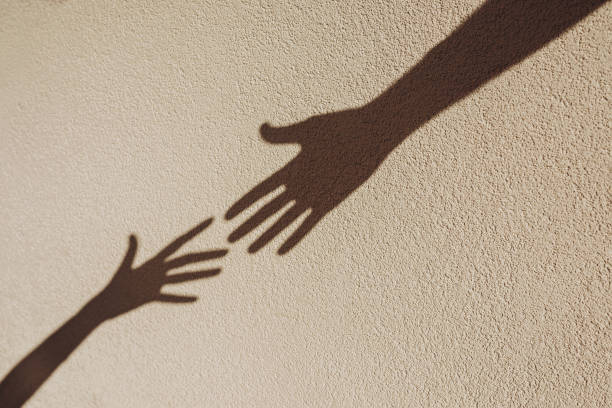 istock Shadows of hands reaching each other on the wall. 2163374913