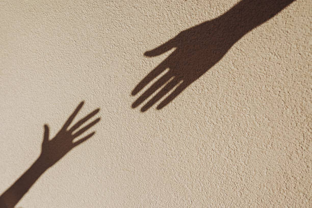 istock Shadows of hands reaching each other on the wall. 2163374938